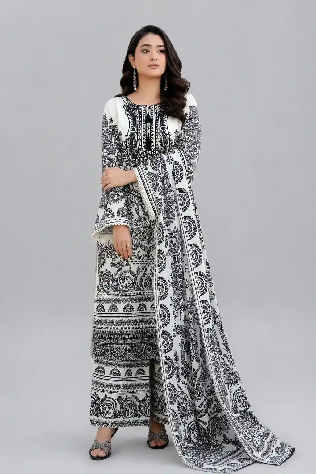 Woman wearing a black and white patterned shalwar kameez on a gray background