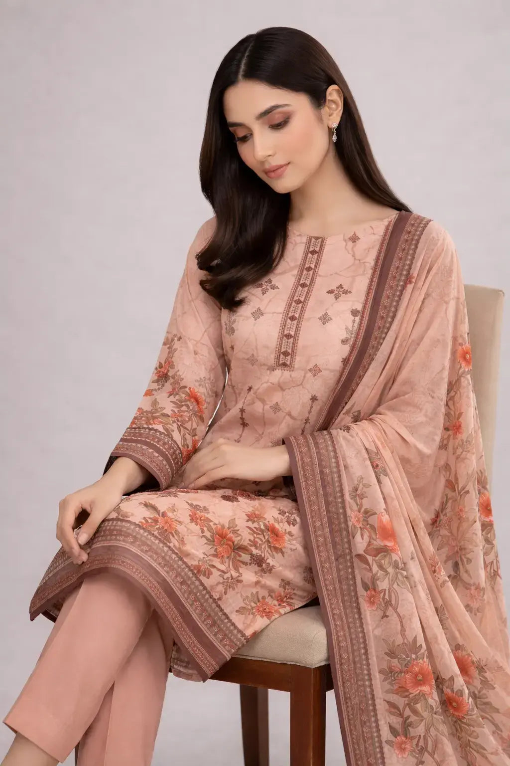 Woman wearing a peach-colored mprints with a matching dupatta on a plain background