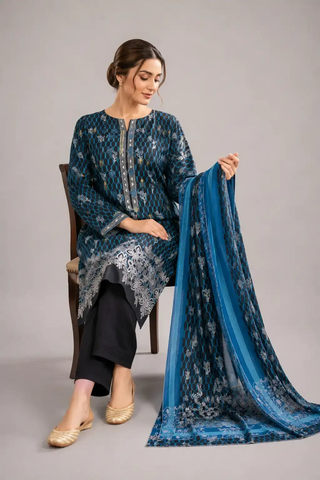 Woman holding a blue printed scarf against, wearing bin saeed lawn dress design 2026