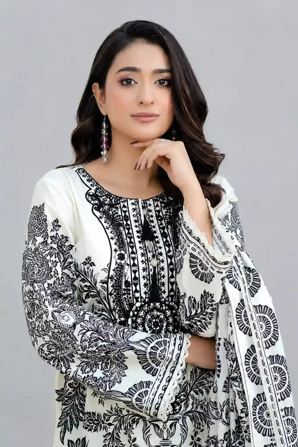 Woman wearing Sobia Nazir lawn a black and white patterned outfit on a gray background